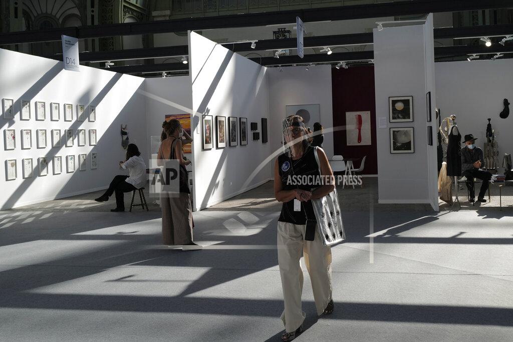 Francois Mori A visitor, wearing a protective face mask as a precaution against the coronavirus, looks on during the opening day of Art Paris at the Grand Palais in Paris, Wednesday Sept. 9, 2020. Fears and restrictions over the coronavirus have caused the cancellation of all of 2020's premiere global art fairs, such as Art Basel, Frieze London, and Art Basel in Miami Beach, stymieing the main commercial artery of the multi-million-dollar industry.But organizers of Art Paris, France's second biggest contemporary art fair, have thrown caution to the wind, and are opening their doors to thousands of visitors from Thursday in the Grand Palais for a four-day show. (AP Photo/Francois Mori)