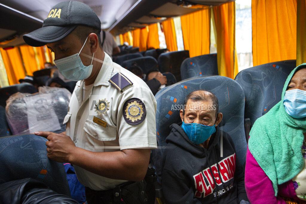 Oliver De Ros A member of the Guatemalan police in search of Honduran migrants checks the documents of bus passengers in Zacapa, Guatemala, Tuesday, Jan. 19, 2021. A once large caravan of Honduran migrants that pushed its way into Guatemala last week had dissipated by Tuesday in the face of Guatemalan security forces. (AP Photo/Oliver de Ros)