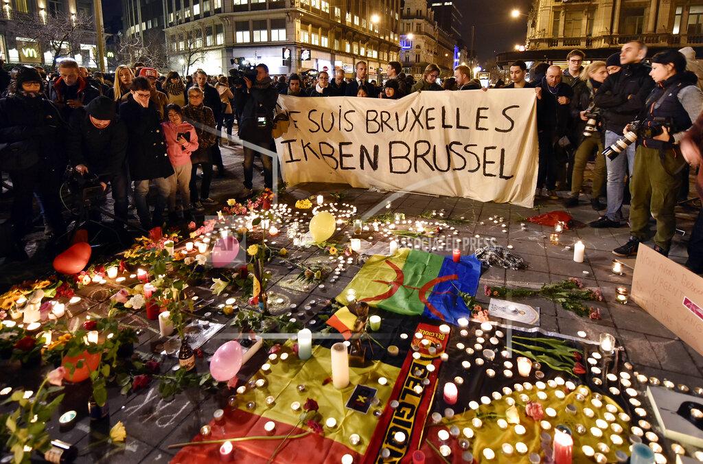 Martin Meissner FILE - In this March 22, 2016 file photo people holding a banner reading "I am Brussels" behind flowers and candles to mourn for the victims at Place de la Bourse in the center of Brussels. Bombs exploded at the Brussels airport and one of the city's metro stations Tuesday, killing and wounding scores of people, as a European capital was again locked down amid heightened security threats. (AP Photo/Martin Meissner, File)