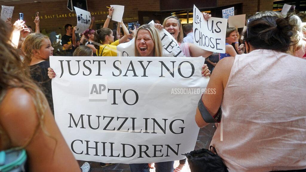 Rick Bowmer FILE - In this Thursday, Aug. 12, 2021 file photo, people celebrate after the Salt Lake County Council voted to overturn a school mask order for kids under the age of 12 issued earlier in the week by the county's top health official. Republican legislators in more than half of U.S. states, spurred on by voters angry over lockdowns and mask mandates, have passed laws to take away powers state and local officials use to protect the public against infectious diseases. (AP Photo/Rick Bowmer)