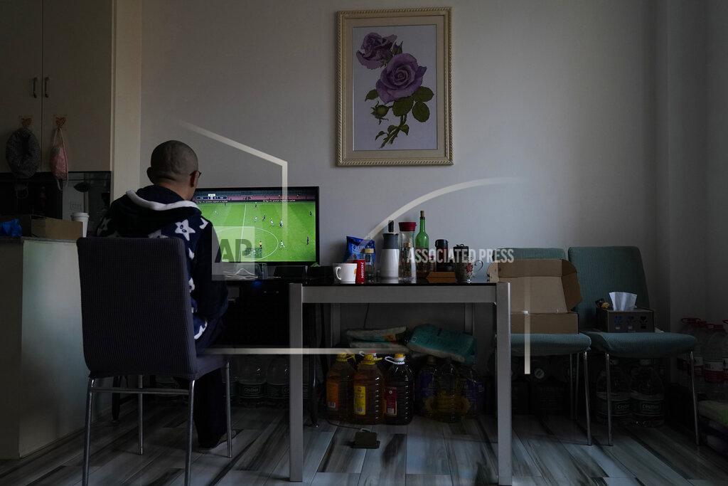 Ng Han Guan Wuhan resident Zhu Tao plays video game near supplies stocked under a table at home in Wuhan in central China's Hubei province on Wednesday, Oct. 21, 2020. Zhu, a government critic, took precautions against the virus early and felt vindicated when the outbreak exploded and the city went into lockdown. But now that the situation is back to something close to normal in Wuhan, Zhu finds himself at odds with his neighbors and the government. (AP Photo/Ng Han Guan)