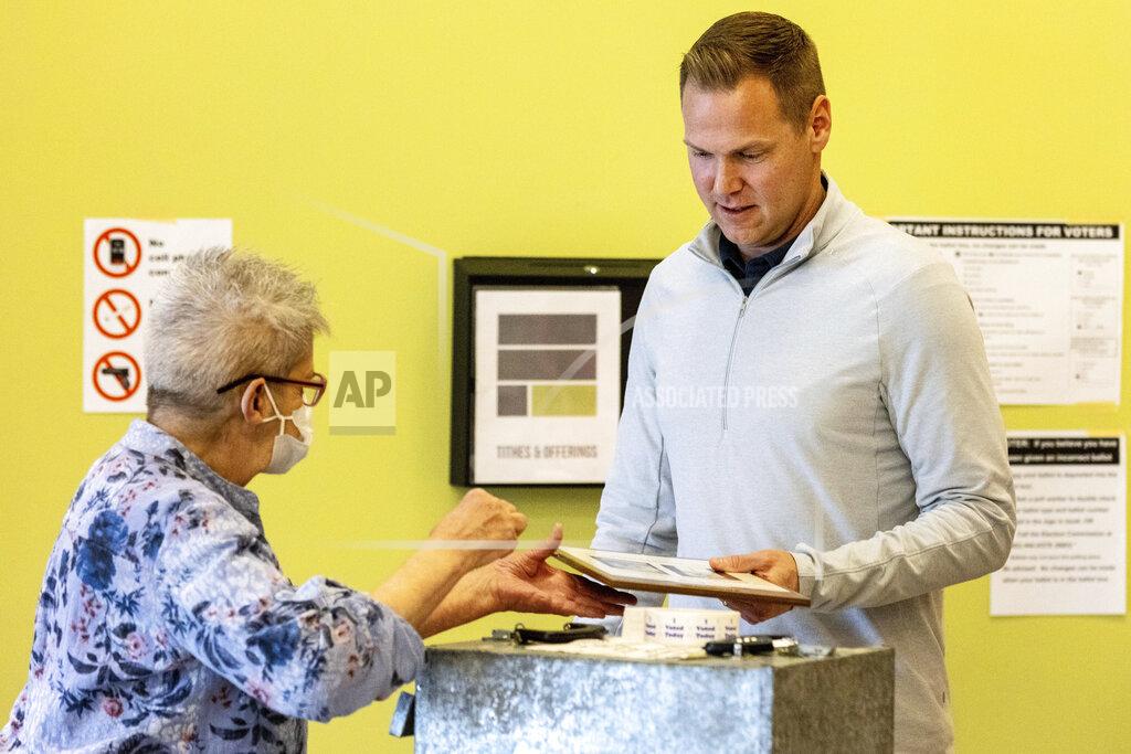 Chris Machian Nebraska Volunteer District Inspector Marilyn Blakemore, left, takes the ballot from State Sen. Brett Lindstrom after he voted in the Nebraska primary at Flatland Church at Flatland Church on Tuesday, May 10, 2022. Lindstrom is running for Governor of Nebraska. (Chris Machian/Omaha World-Herald via AP)