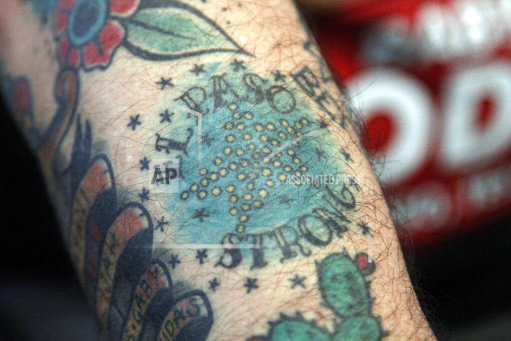 Cedar Attanasio In this Thursday, May 21, 2020, photo, artist Charlie Monarrez, 46, shows an "El Paso Strong" tattoo in
El Paso, Texas, that he designed in the wake of the Aug. 3 mass shooting at a Walmart. Montarrez and his partner Monica Monarrez sold thousands of T-shirts with the design to raise tens of thousands of dollars for the dozens of shooting victims. (AP Photo/Cedar Attanasio)