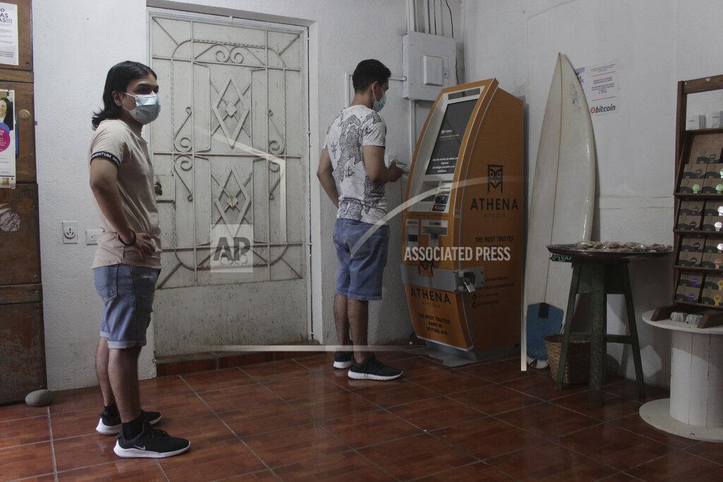 Salvador Melendez Eduardo Magaña, right, uses the first ATM designed to withdraw cash through the cryptocurrency App "Bitcoin Beach" on El Zonte Beach in Tamanique, El Salvador, Wednesday, June 9, 2021. In this beach community, a nongovernmental organization with the financial backing of an anonymous Bitcoin donor has been trying to create a small-scale cryptocurrency economy, and could serve as a showcase for the gains and struggles to introduce a phone-based cryptocurrency as the country embarks on a nationwide experiment after making Bitcoin legal tender this week. (AP Photo/Salvador Melendez)