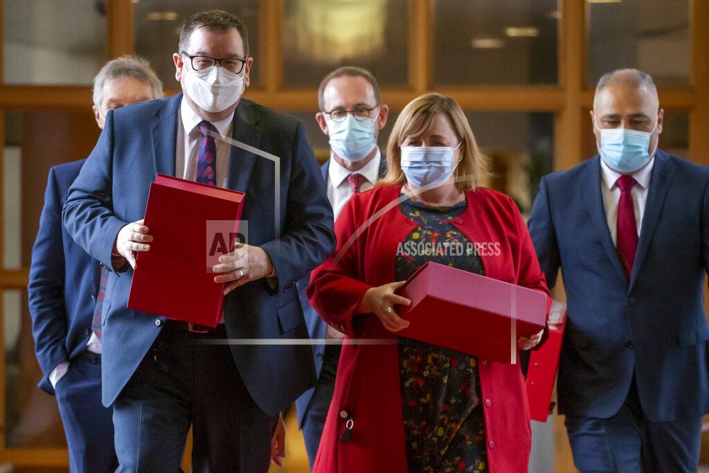 Mark Mitchell New Zealand Finance Minister Grant Robertson, front left, is on his way to present his budget to Parliament with ministers, from left, David Parker, obscured, Andrew Little, Megan Woods, and Peeni Henare, right, in Wellington, New Zealand, Thursday, May 19, 2022. New Zealand's government said Thursday it will hand out an extra few hundred dollars to about half of all adults to help them navigate what it describes as "the peak of the global inflation storm." (Mark Mitchell/NZ Herald via AP)