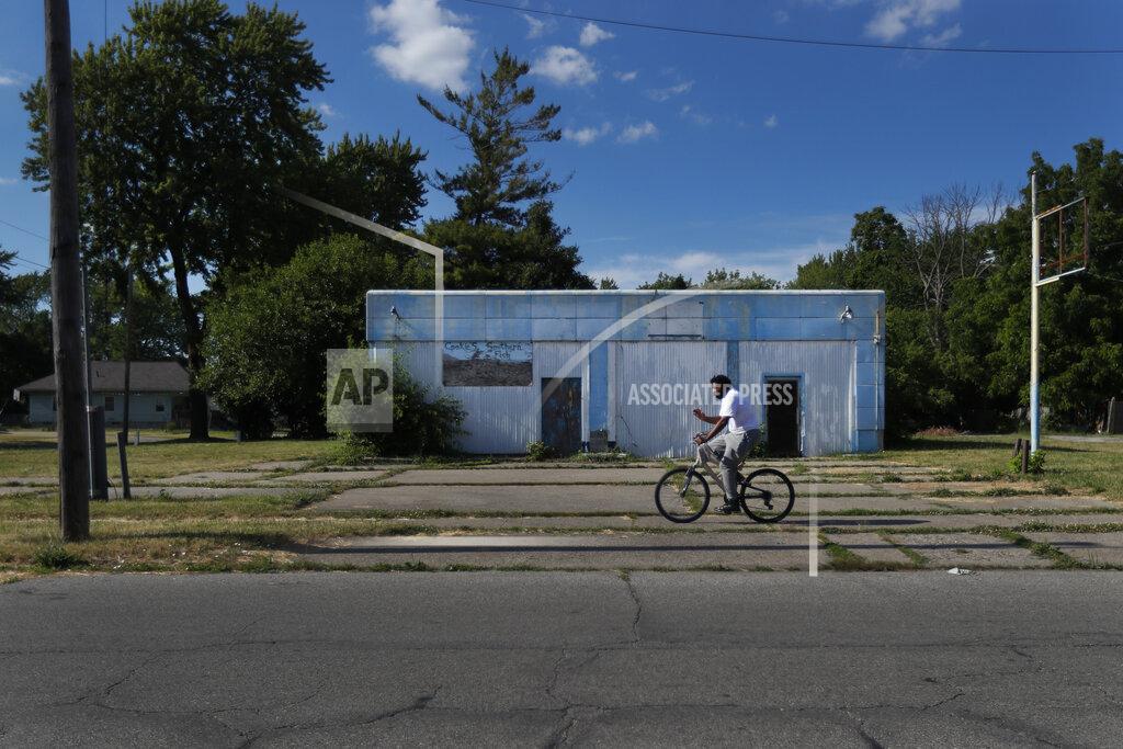 Charles Rex Arbogast A man rides his bicycle past an abandoned service station in the impoverished east side neighborhood of Saginaw, Mich., on Monday, June 29, 2020. It's difficult to celebrate America in Saginaw this July 4th. The deadly pandemic kept families apart. A brutal recession means money is tight. Weeks of protest over racial inequality left many debating what exactly should be celebrated and what must be changed. (AP Photo/Charles Rex Arbogast)