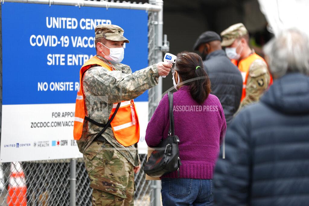 Shafkat Anowar CORRECTS MONTH TO MARCH NOT FEBRUARY - A National Guard member checks the temperature of people entering the United Center mass COVID-19 vaccination site on Wednesday, March 10, 2021, in Chicago. The site will administer 6,000 shots per day at full capacity and will remain open seven days a week for eight weeks. (AP Photo/Shafkat Anowar)