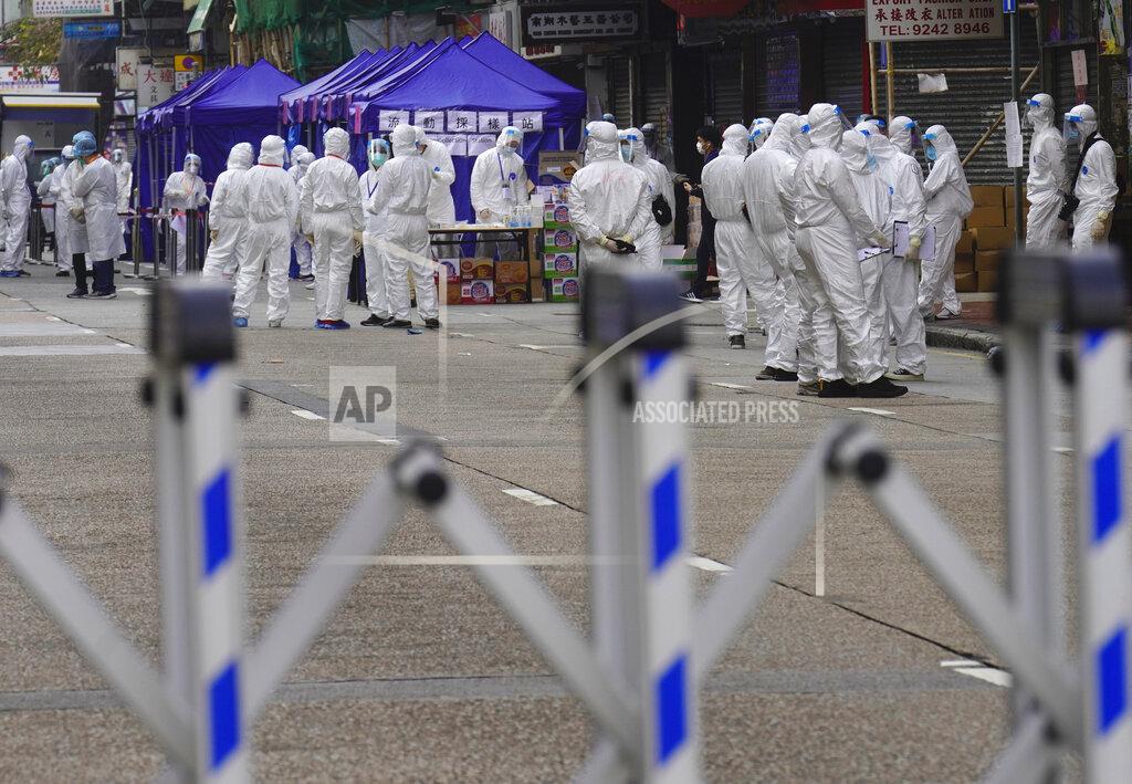 Vincent Yu Government investigators wearing protective suits gather in the Yau Ma Tei area in Hong Kong, Saturday, Jan. 23, 2021. Thousands of Hong Kong residents were locked down Saturday in an unprecedented move to contain a worsening outbreak in the city, authorities said. (AP Photo/Vincent Yu)