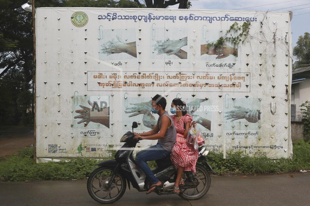 Uncredited People wearing face masks to help curb the spread of the coronavirus ride a motorcycle past a Health Ministry public information campaign billboard about proper hand washing in Shwe Pyi Thar township in Yangon, Myanmar Wednesday, July 28, 2021. (AP Photo)