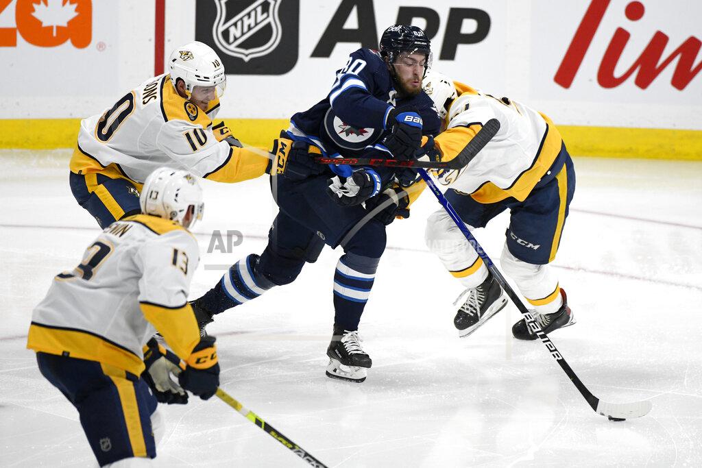 Fred Greenslade Winnipeg Jets' Pierre-Luc Dubois (80) gets past Nashville Predators' Colton Sissons (10) and Dante Fabbro (57) during the second period of NHL hockey game action in Winnipeg, Manitoba, Saturday, Oct. 23, 2021. (Fred Greenslade/The Canadian Press via AP)