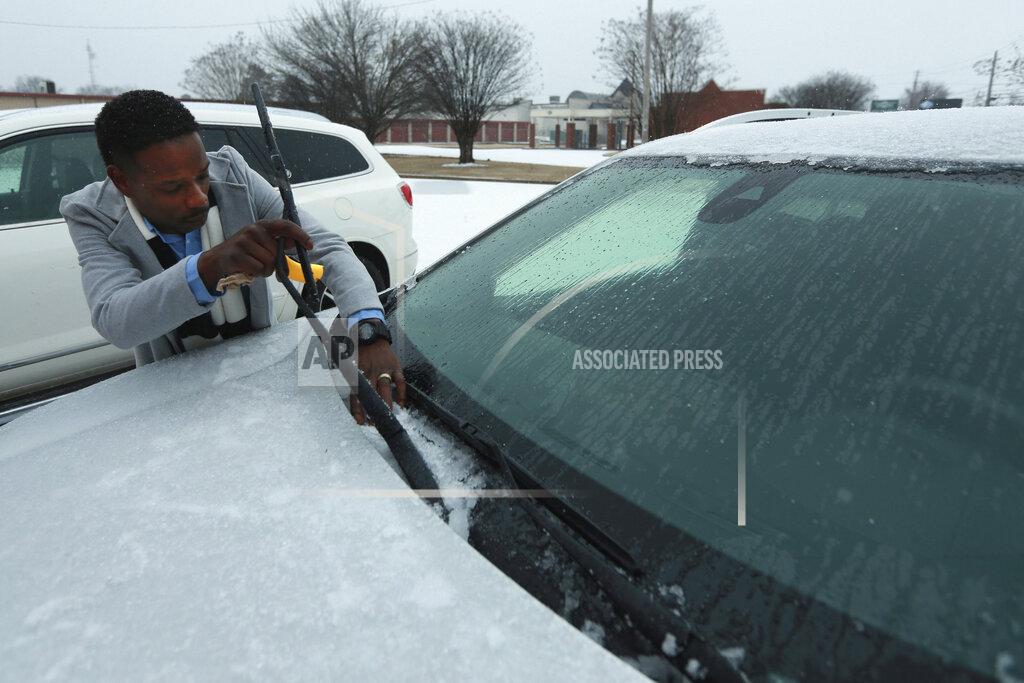 Mitra Bumphis, District Managet of KFC on West Main Street, cleans the base of his windshield to keep his wiper blades from freezing to the glass as he lets his car warm up at the West Main Street KFC early Monday morning in Tupelo. (Adam Robison/The Northeast Mississippi Daily Journal via AP)