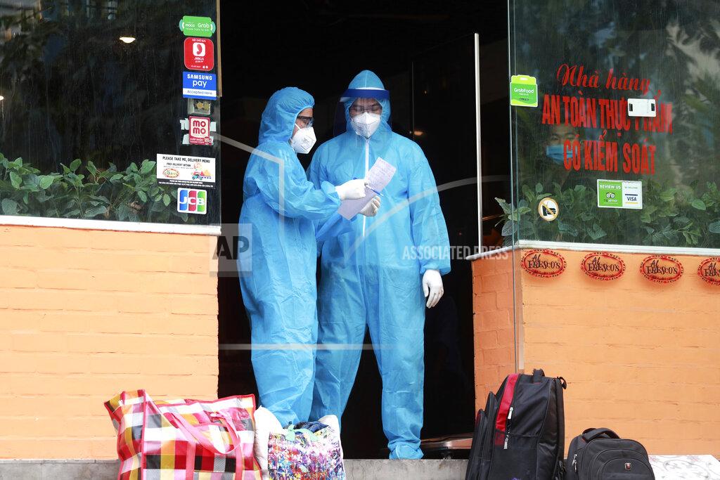 Hau Dinh Health workers share a note at a restaurant where a worker is suspected to have COVID-19 in Hanoi, Vietnam on Wednesday, July 29, 2020. Vietnam intensifies protective measures as the number of locally transmissions, starting at a hospital in the popular beach city of Da Nang, keeps increasing since the weekend. (AP Photo/Hau Dinh)