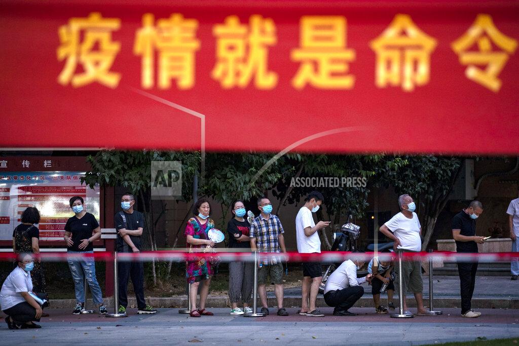 Uncredited Residents line up for Covid-19 tests near a banner with the words "Epidemic is the Order" in Wuhan in central China's Hubei province Tuesday, Aug. 3, 2021. China's worst coronavirus outbreak since the start of the pandemic a year and a half ago escalated Wednesday with dozens more cases around the country, the sealing-off of one city and the punishment of its local leaders. (Chinatopix Via AP)