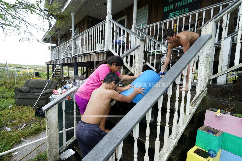 Gerald Herbert Lerryn Brune, 10, center, Terren Dardar, 17, right, and Dayton Verdin, 14, move barrels of rainwater they collected from Tropical Storm Nicholas, in the aftermath of Hurricane Ida in Pointe-aux-Chenes, La., Tuesday, Sept. 14, 2021. They have had no running water since the hurricane, and collected 140 gallons of rainwater in two hours from the tropical storm, which they filter and pump into their house for showers. (AP Photo/Gerald Herbert)
