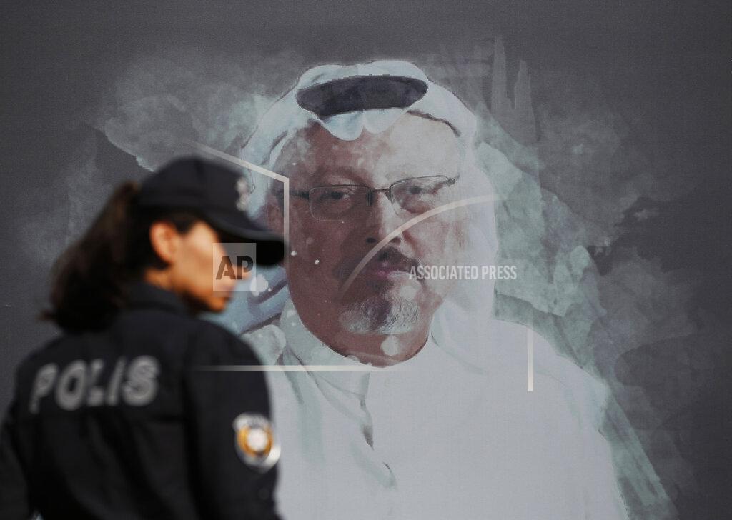 FILE - In this Wednesday, Oct. 2, 2019 file photo, a Turkish police officer walks past a picture of slain Saudi journalist Jamal Khashoggi prior to a ceremony, near the Saudi Arabia consulate in Istanbul, marking the one-year anniversary of his death. On Wednesday, March 25, 2020, Turkish prosecutors have formally charged two former aides of Saudi Crown Prince Mohammed bin Salman and 18 other Saudi nationals over the 2018 killing of Khashoggi. All suspects however, have left Turkey and Saudi Arabia has rejected Turkish calls for their return to face trial in Turkey. (AP Photo/Lefteris Pitarakis, File)