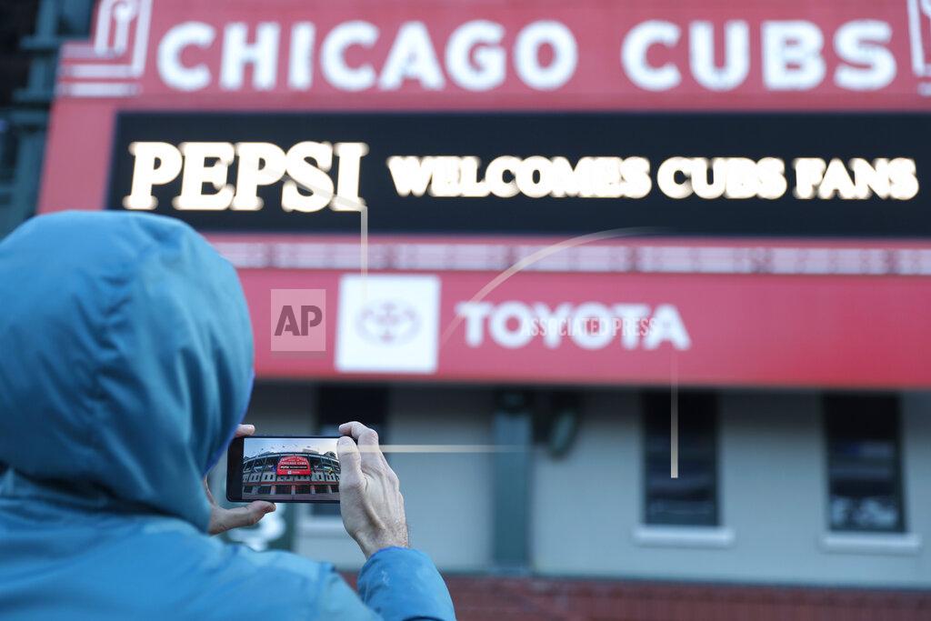 Shafkat Anowar A person takes a photo of the Wrigley Field marquee, early morning on the opening day baseball game between the Chicago Cubs and the Pittsburgh Pirates, Thursday, April 1, 2021 at Chicago. From New York to Seattle and everywhere in between, it’s a much different opening day in 2021. Fans are back at the ballpark after they were shut out during the regular season last year because of the coronavirus pandemic. (AP Photo/Shafkat Anowar)