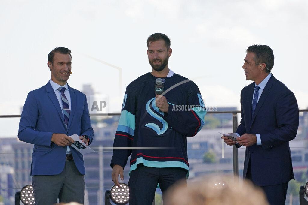 Ted S. Warren Chris Dreidger, center, a goalie from the Florida Panthers, stands with ESPN NHL hockey draft hosts Dominic Moore, left, and Chris Fowler as he is introduced Wednesday, July 21, 2021, as a new player for the Seattle Kraken during the team's expansion draft event in Seattle. (AP Photo/Ted S. Warren)