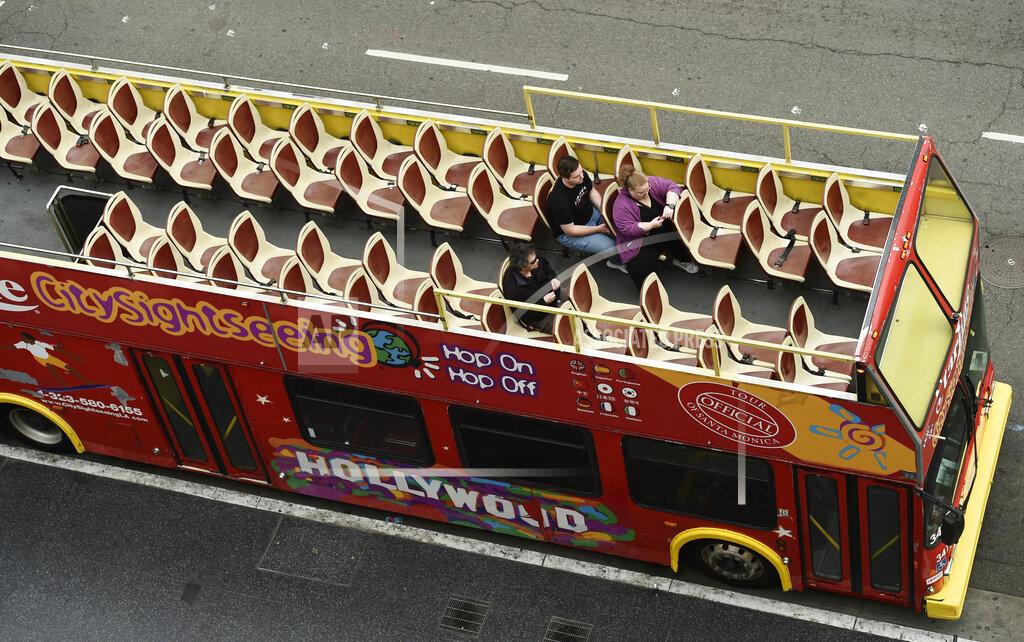 Chris Pizzello FILE - In this March 12, 2020, file photo, tourists sit in a mostly empty sightseeing bus on Hollywood Boulevard in the Hollywood section of Los Angeles. Los Angeles and San Francisco are poised Tuesday, May 4, 2021, to be the only major urban areas in the state to meet guidelines to move into the least-restrictive tier. (AP Photo/Chris Pizzello, File)