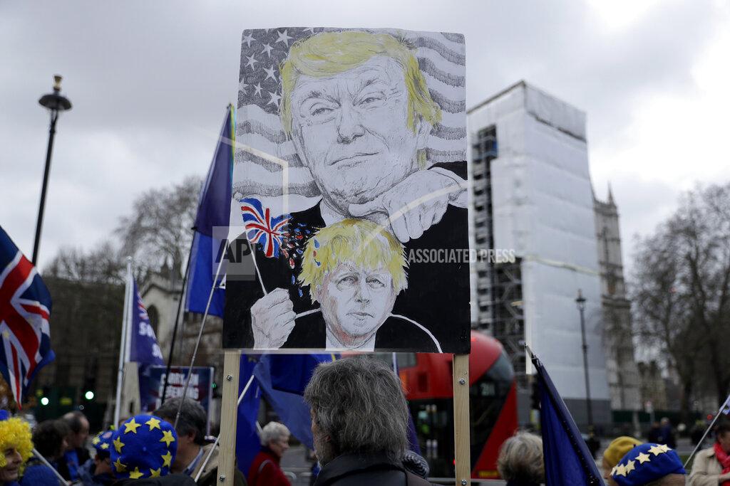 Matt Dunham FILE - In this Jan. 8, 2020 file photo remain in the European Union, anti-Brexit protesters, including one with a placard depicting British Prime Minister Boris Johnson under the thumb of U.S. President Donald Trump, demonstrate outside the Houses of Parliament in London, on the day of Prime Minister's Questions taking place inside. (AP Photo/Matt Dunham, File)
