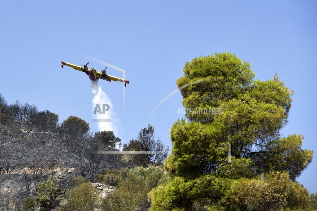 Andreas Alexopoulos An aircraft drops water in Lampiri village, east of Patras city, Greece, Sunday, Aug. 1, 2021. A wildfire that broke out Saturday in western Greece forced the evacuation of four villages and people on a beach by the Fire Service, the Coast Guard and private boats, authorities said. (AP Photo/Andreas Alexopoulos)