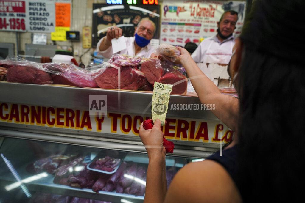 Fernando Llano A customer pays with a 200 peso bill (about 10 dollars) to buy meat at Medellin Market in Mexico City, Monday, May 9, 2022. Inflation in Mexico accelerated in April that brought the annual rate to 7.68%, the highest in two decades. (AP Photo/Fernando Llano)