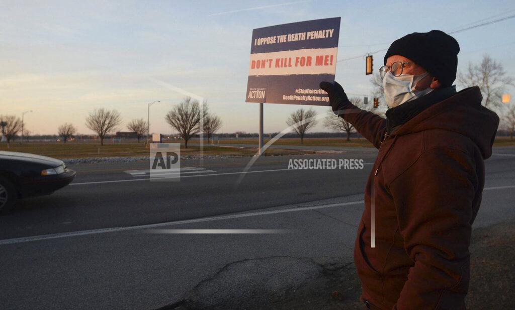 Death penalty opponent Wes Janz, of Indianapolis, holds up a sign for passing motorists to read as he and others protest the scheduled execution of Lisa Montgomery, Tuesday, Jan. 12, 2021, near the Federal Correctional Complex in Terre Haute, Ind. An appeals court granted a stay of execution Tuesday for Montgomery, convicted of killing a pregnant woman and cutting the baby from her womb in the northwest Missouri town of Skidmore in 2004. (Joseph C. Garza/The Tribune-Star via AP)