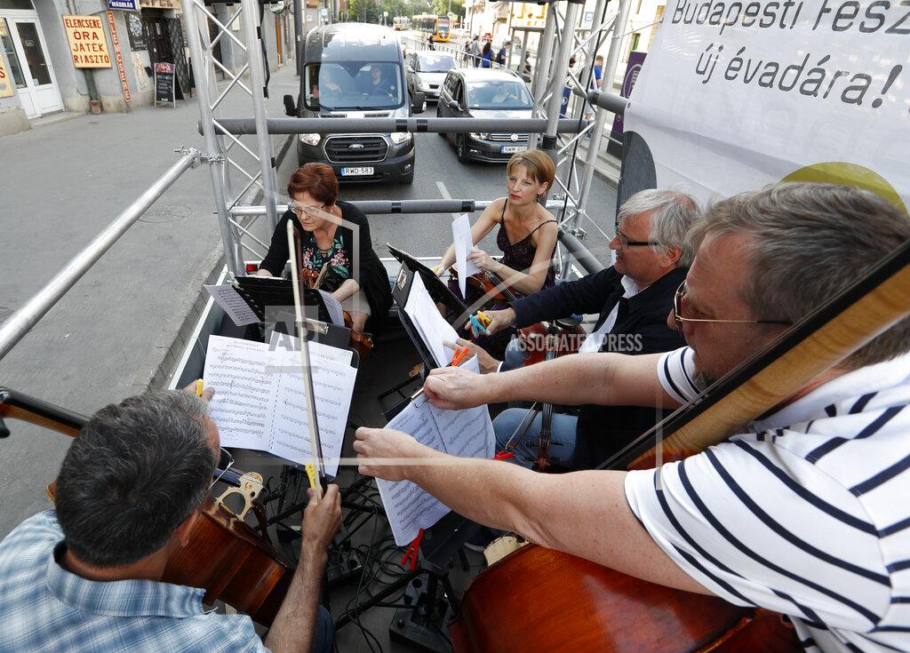 Laszlo Balogh Members of the Budapest Festival Orchestra play music on the back of a truck while driving through downtown Budapest, Hungary, Wednesday June 9, 2021. The prestigious orchestra, founded and led by renowned composer Ivan Fischer, took to the streets as five members of the orchestra performed classical music to motorists and passers-by. The musical parade was aimed at encouraging Hungarians to start returning to live performances in concert halls as the pandemic wanes, after more than a year in which people were homebound and forced to take in their culture online. (AP Photo/Laszlo Balogh)