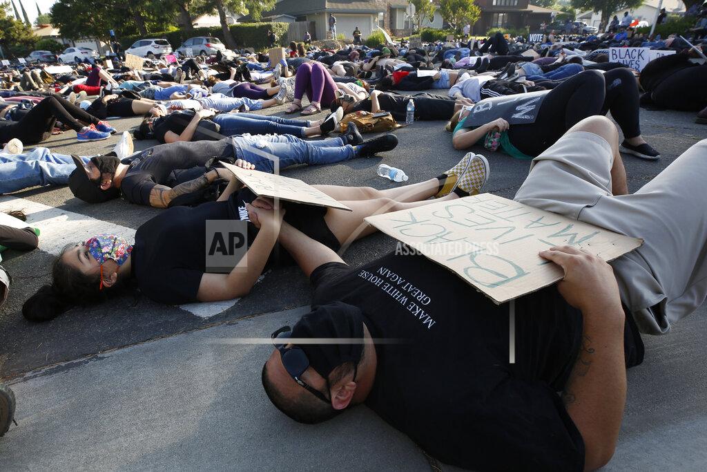 Rich Pedroncelli Aliana Gayton, left, holds hands with her father, Ronaldo Gayton, as they join other protesters Friday, June, 5, 2020, in lying down silently for 8 minutes and 46 seconds during a demonstration to honor George Floyd, near the home of Sacramento Mayor Darrell Steinberg in Sacramento, Calif. Floyd, a black man, died after being restrained by Minneapolis police officers on May 25. (AP Photo/Rich Pedroncelli)