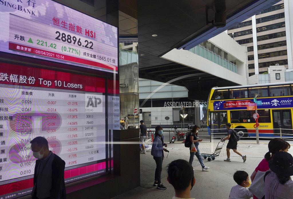Vincent Yu People walk past a bank's electronic board showing the Hong Kong share index in Hong Kong Thursday, April 8, 2021. Shares were mostly higher in Asia on Thursday after a mixed close on Wall Street, where gains for several Big Tech stocks nudged the S&P 500 to a second record high in three days.(AP Photo/Vincent Yu)