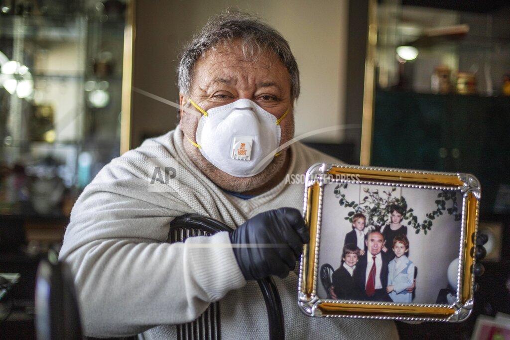 David Goldman Michael Tokar holds a picture of his father, David Tokar, as he cleans out his apartment after he died from complications caused by coronavirus, in the Brooklyn borough of New York, Sunday, April 12, 2020. "He was born 92 years ago," said Tokar, reciting a collection of facts that form a portrait. "He collected stamps. He loved the racetrack. He adored his grandchildren." (AP Photo/David Goldman)