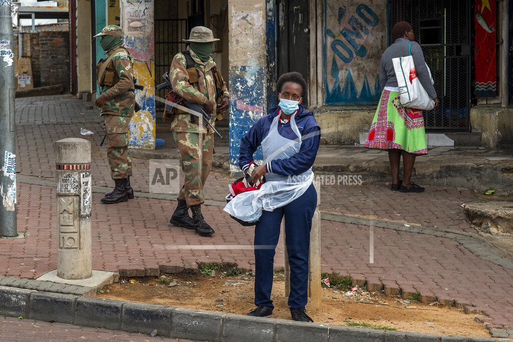 Jerome Delay A health worker stands outside a stadium where residents from the Alexandra township in Johannesburg have lined up to be tested for COVID-19 Monday, April 26, 2020. South Africa will began a phased easing of its strict lockdown measures on May 1, although its confirmed cases of coronavirus continue to increase. (AP Photo/Jerome Delay)