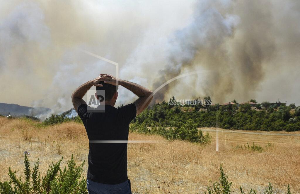 Uncredited A man watches wildfires in Kacarlar village near the Mediterranean coastal town of Manavgat, Antalya, Turkey, Saturday, July 31, 2021. The death toll from wildfires raging in Turkey's Mediterranean towns rose to six Saturday after two forest workers were killed, the country's health minister said. Fires across Turkey since Wednesday burned down forests, encroaching on villages and tourist destinations and forcing people to evacuate. (AP Photo)