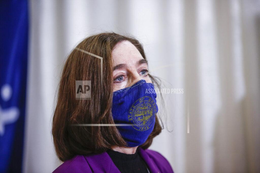 FILE - In this Jan. 13, 2021, file photo, Oregon Gov. Kate Brown visits the Marion County and Salem Health COVID-19 vaccination clinic in Salem, Ore. Brown said Friday, March 5, 2021, that she is issuing an executive order mandating that all public schools provide universal access to in-person learning by the month's end for students up to fifth grade and by mid-April for older students. (Abigail Dollins/Statesman-Journal via AP, Pool, File)