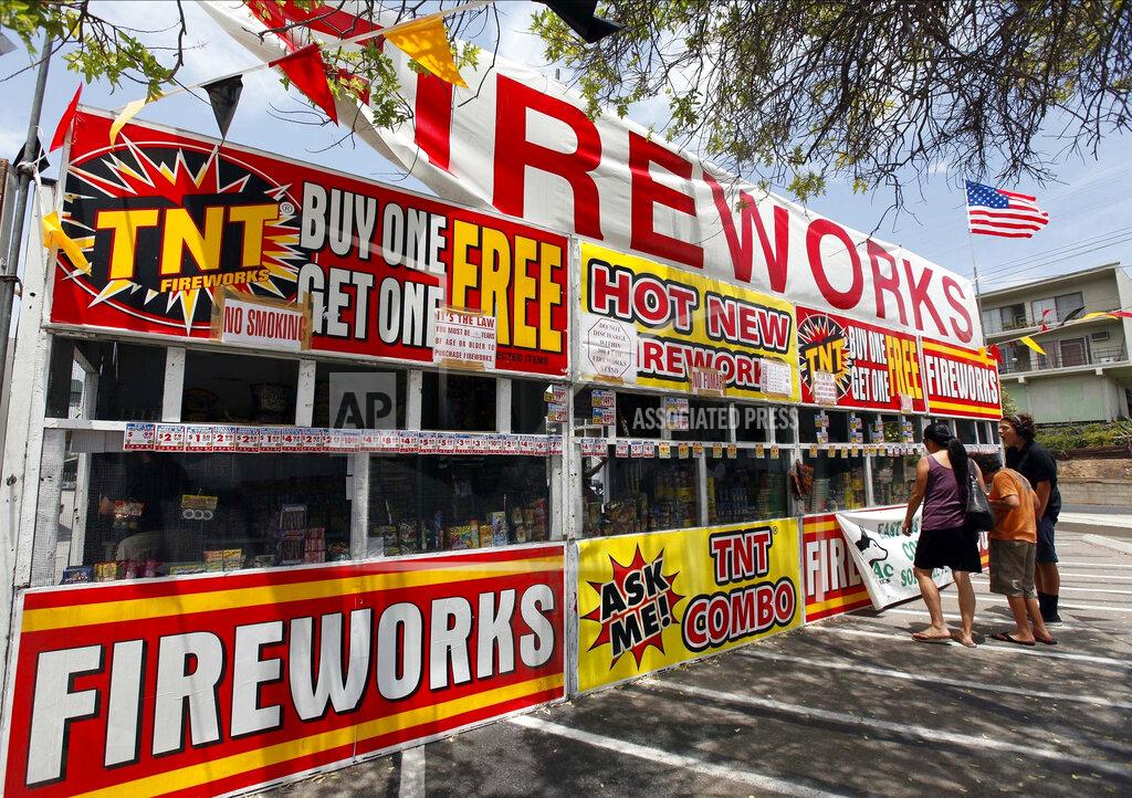 FILE - In this July 2, 2013, file photo, a family purchases fireworks at a TNT Fireworks stand in the City of Monterey Park, Calif. With fewer professional celebrations on July 4, 2020, due to the coronavirus pandemic, many Americans are bound to shoot off fireworks in backyards and at block parties. And they already are: Sales have been booming. (AP Photo/Nick Ut, File)