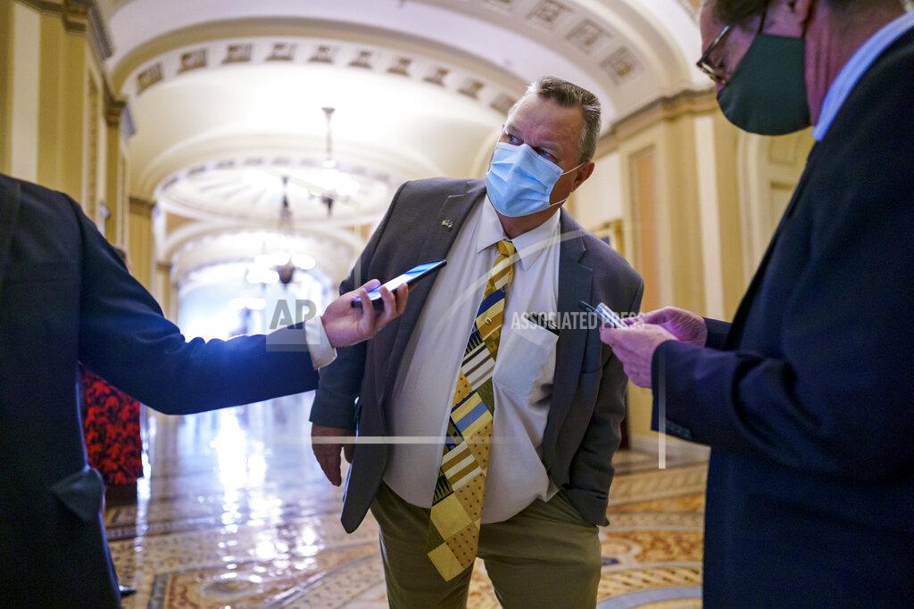 J. Scott Applewhite Sen. Jon Tester, D-Mont., peers around a doorway while speaking with reporters during a vote on amendments in the $1 trillion bipartisan infrastructure bill, at the Capitol in Washington, Tuesday, Aug. 3, 2021. (AP Photo/J. Scott Applewhite)