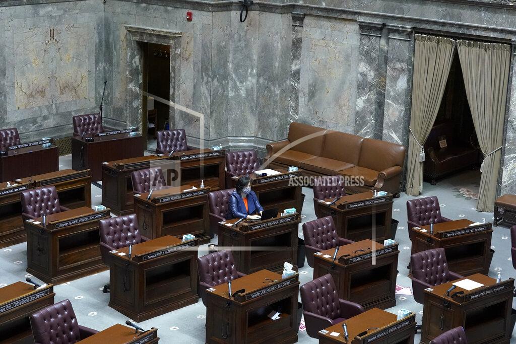 Ted S. Warren FILE - In this Jan. 13, 2021 file photo, Washington Sen. Emily Randall, D-Bremerton, works at her desk on the otherwise empty Senate floor, at the Capitol in Olympia, Wash., during a joint session of the Washington Legislature being held remotely. The 2021 session of the Washington Legislature ended Sunday, April 25 and lawmakers had no shortage of weighty topics to consider while having to conduct their work amid a pandemic that meant most meetings and votes were conducted remotely. The Capitol building was also closed to the public since last year due to the COVID-19 pandemic, and was surrounded by security fencing and national guard members at times due to fears of protests. (AP Photo/Ted S. Warren, File)