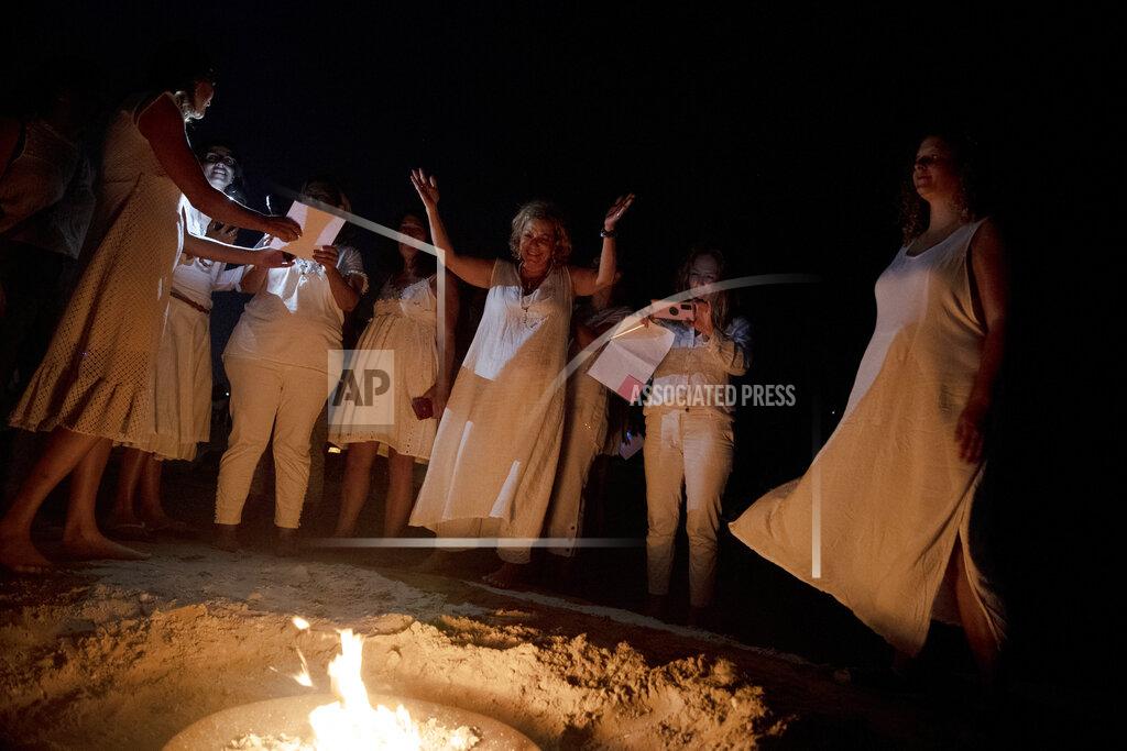 Maya Alleruzzo Women take part in a Tashlich ceremony, where they wrote down things they want to release before casting them into a fire, on the beach in Tel Aviv, Israel, Tuesday, Sept. 14, 2021. Tashlich, which means 'to cast away' in Hebrew, is the practice by which Jews go to a large flowing body of water and symbolically 'throw away' their sins by throwing a piece of bread, or similar food, into the water before the Jewish holiday of Yom Kippur, the holiest day in the Jewish year which starts at sundown Wednesday. (AP Photo/Maya Alleruzzo)