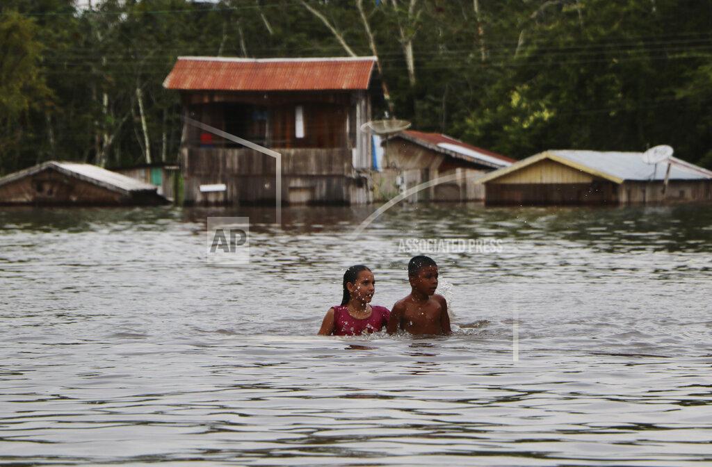 Edmar Barros Residents move through on a flooded street in Anama, Amazonas state, Brazil, Thursday, May 13, 2021. (AP Photo/Edmar Barros)