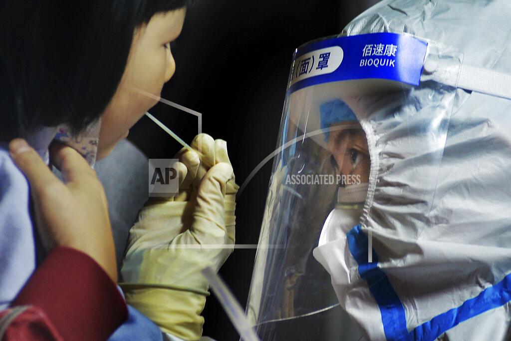 Uncredited A medical staff takes a swab from a child near a residential area in Qingdao in east China's Shandong province on Tuesday, Oct. 13, 2020. A hospital president and the director of the health commission in the northern Chinese city of Qingdao have been fired after China's latest coronavirus outbreak, authorities said Thursday, Oct. 15, 2020. (Chinatopix via AP)