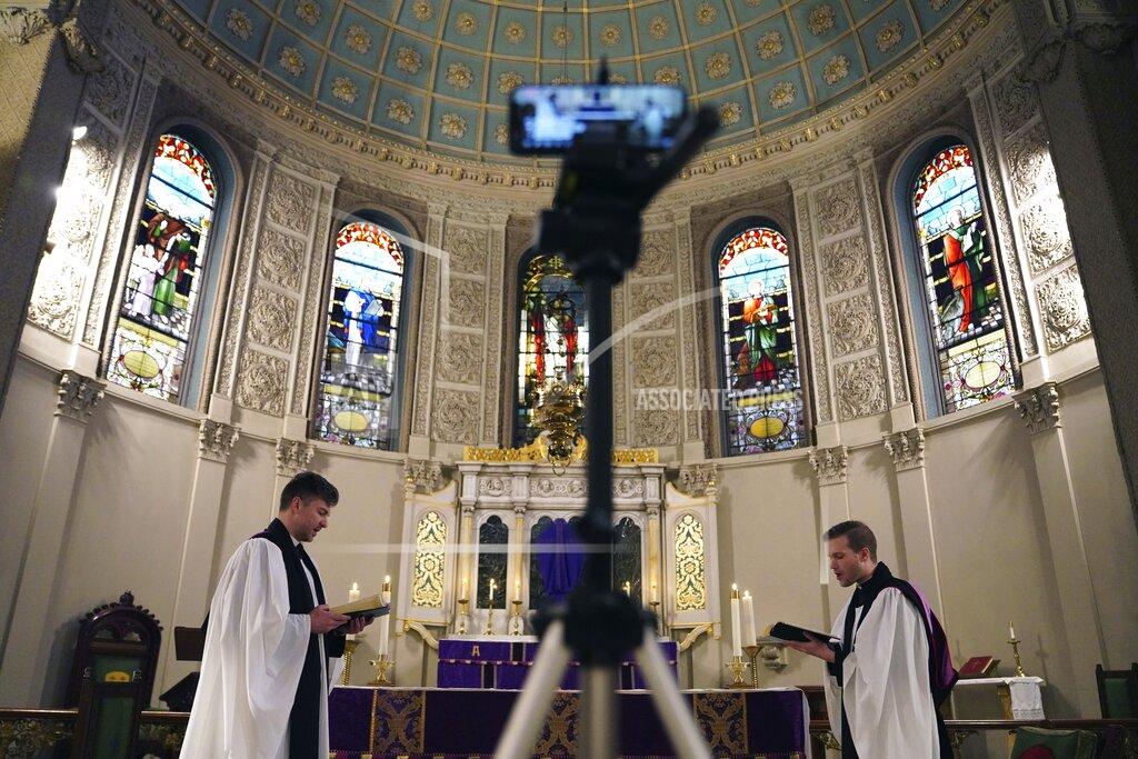 FILE - In this March 29, 2020 file photo, the Rev. Steven Paulikas, right, and curate Spencer Cantrell deliver an Evening Prayer service over Facebook Live in the Brooklyn borough of New York, amid the global COVID-19 coronavirus pandemic. Pastors across the country say they and their congregations have responded with creativity and resiliency — and invigorated community spirit — even as the outbreak forced widespread cancellations of in-person services. (AP Photo/Emily Leshner)