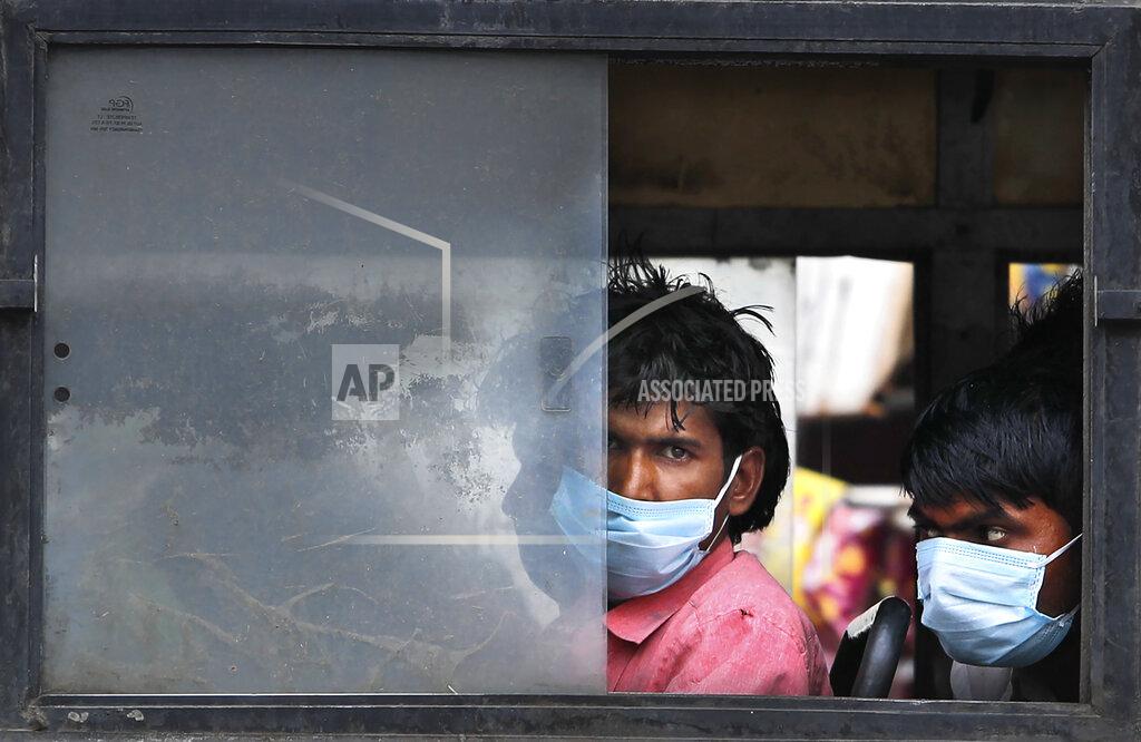 Manish Swarup Migrant laborers sit in a bus to travel to their villages following a six-day lockdown put into place to control the rising cases of coronavirus infections, in New Delhi, India, Tuesday, April 20, 2021. India recorded over 250,000 new infections and over 1,700 deaths in the past 24 hours alone, and the U.K. announced a travel ban on most visitors from the country this week. (AP Photo/Manish Swarup)