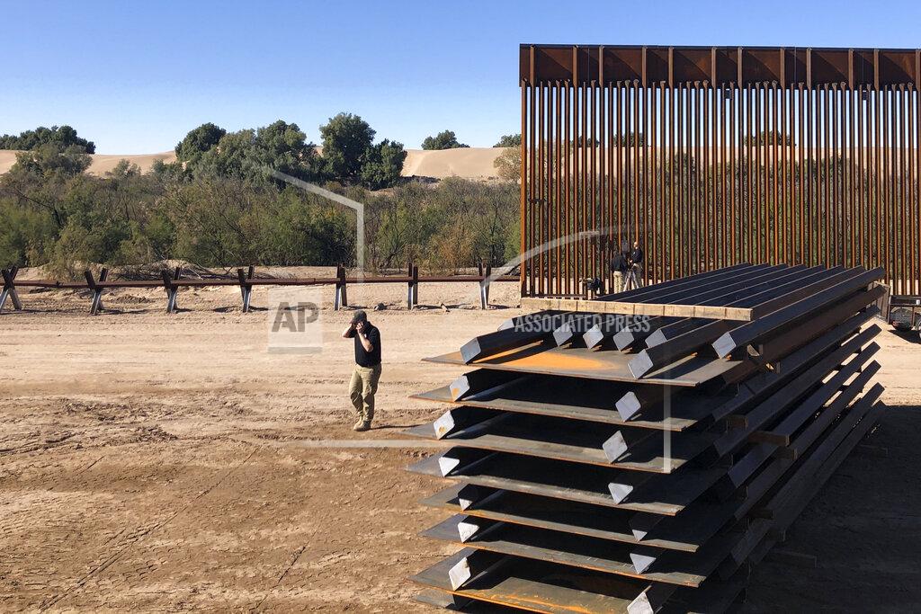 Elliot Spagat A man passes new border wall sections, right, as they replace the old fencing, left, Friday, Jan. 10, 2020, near Yuma, Arizona. Top Trump administration officials will visit South Texas five days before Election Day to announce they have completed 400 miles of U.S.-Mexico border wall, attempting to show progress on perhaps the president's best-known campaign promise four years ago. But most of the wall went up in areas that already had smaller barriers. (AP Photo/Elliot Spagat)