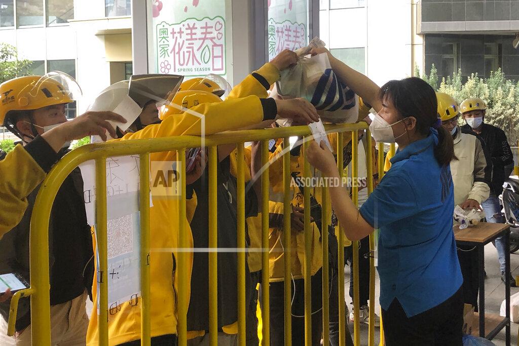 Chen Si A supermarket employee hands over a bag of groceries to a deliveryman in Shanghai, China, Monday, May 23, 2022. Shanghai reported 480,000 people were still confined to their homes due to COVID-19 precautions, while 1.59 million were permitted to move around their neighborhoods and 21.2 million were under lighter restrictions. (AP Photo/Chen Si)