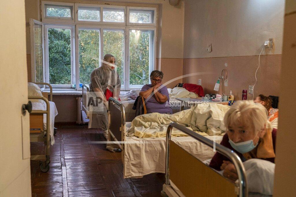 Evgeniy Maloletka A medical worker speaks to a coronavirus patient at a hospital in Stebnyk, Ukraine, on Tuesday, Sept. 29 2020. As coronavirus cases increase, every bed in the hospital in this city in western Ukraine is in use and its chief doctor is watching the surge with alarm and anguish. (AP Photo/Evgeniy Maloletka)