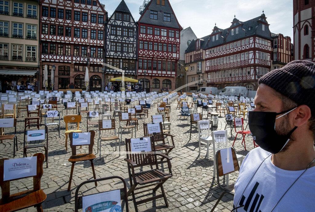 Michael Probst FILE - In this April 24, 2020 file photo, a man with a face mask watches empty chairs with names of bars and restaurants on the Roemerberg square in Frankfurt, Germany. More than 50,000 people have died after contracting COVID-19 in Germany, a number that has risen swiftly over recent weeks as the country has struggled to bring down infection figures. (AP Photo/Michael Probst, File)