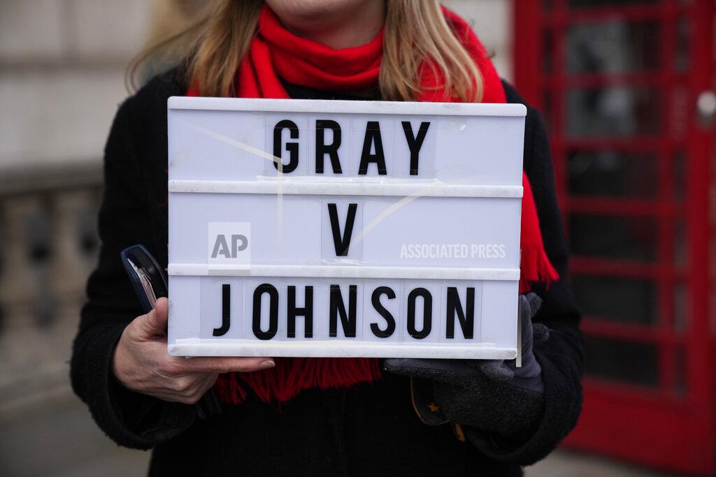 Matt Dunham FILE - An anti-Boris Johnson protester holds a placard as a reference to the Sue Gray report, on the junction of Parliament Street and Parliament Square, in London, Wednesday, Jan. 26, 2022. Gray is a senior but previously obscure civil servant who may hold British Prime Minister Boris Johnson's political future in her hands. She has the job of investigating allegations that the prime minister and his staff attended lockdown-flouting parties on government property. AP Photo/Matt Dunham, File)