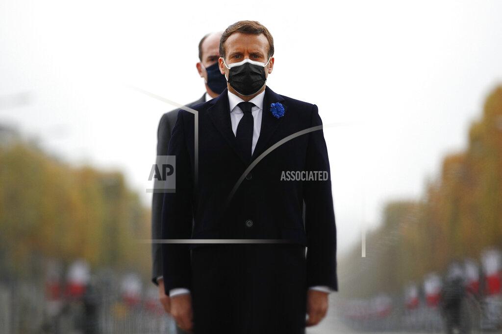 Yoan Valat French President Emmanuel Macron, center foreground, and French Prime Minister Jean Castex, center background, stand at the tomb of the unknown soldier under the Arc de Triomphe during Armistice Day ceremonies marking the end of World War I, in Paris, Wednesday, Nov. 11, 2020. French President Emmanuel Macron is commemorating the 102nd anniversary of the armistice ending World War I and honoring all those who have died for France in two elaborate, solemn ceremonies Wednesday. (Yoan Valat/Pool via AP)