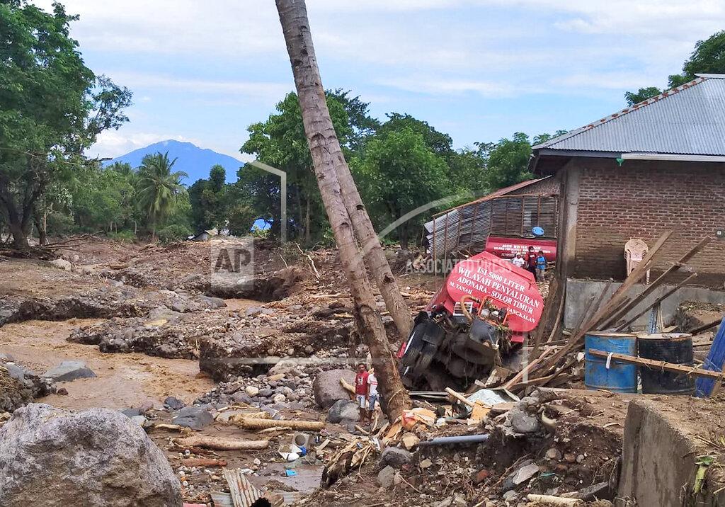 Rofinus Monteiro People survey the damage near the wreckages of trucks at a flood-affected village in Waewerang on Adonara Island, East Nusa Tenggara province, Indonesia, Wednesday, April 7, 2021. Multiple disasters triggered by Tropical Cyclone Seroja in eastern Indonesia and neighboring East Timor have left a number of people dead or missing. (AP Photo/Rofinus Monteiro)