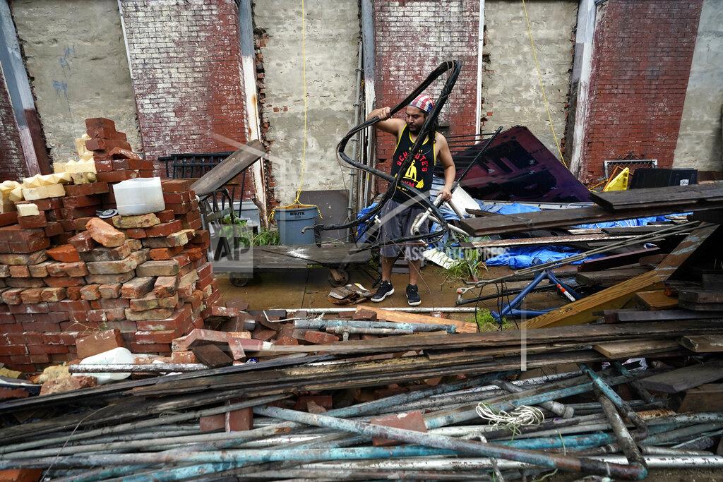 David J. Phillip Adrian Bentancourt cleans up debris from a fence that was blown down by Hurricane Nicholas Tuesday, Sept. 14, 2021, in Galveston, Texas. (AP Photo/David J. Phillip)