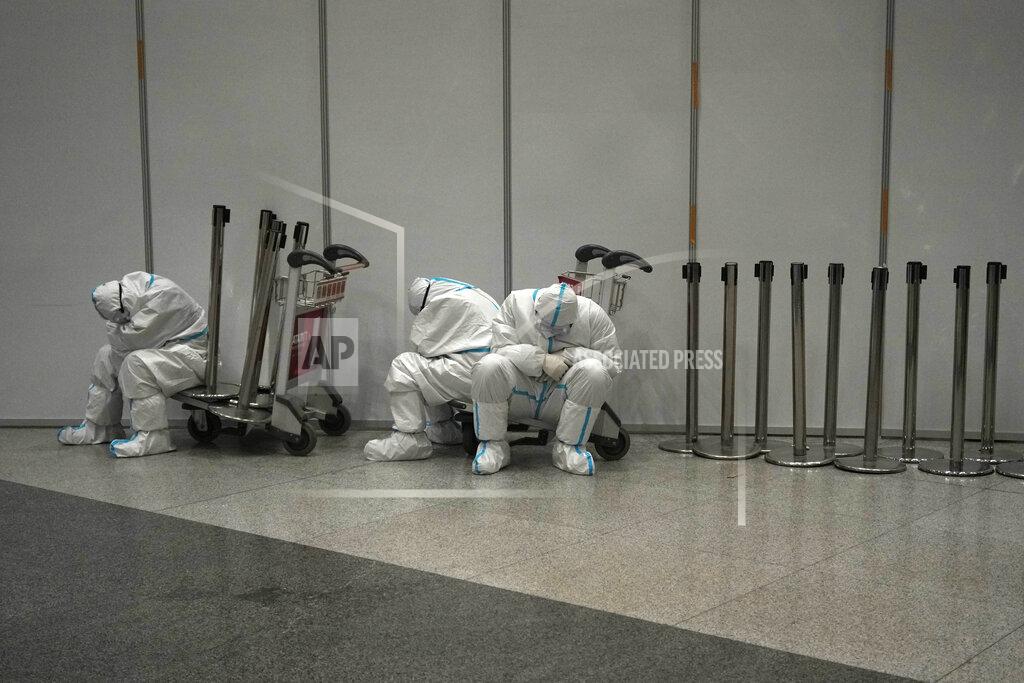 Alessandra Tarantino Olympic workers in protective clothing rest after they helped travelers at Beijing Capital International airport after the 2022 Winter Olympics, Monday, Feb. 21, 2022, in Beijing, China. (AP Photo/Alessandra Tarantino)
